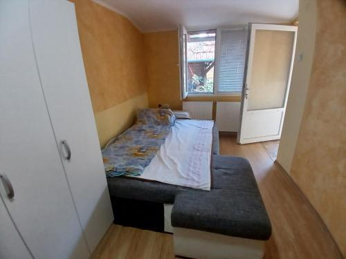 a small bedroom with a bed and a bench at sobe DALE in Subotica