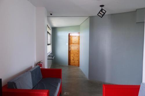 a living room with a red couch and a door at AV Suites in Puerto Galera
