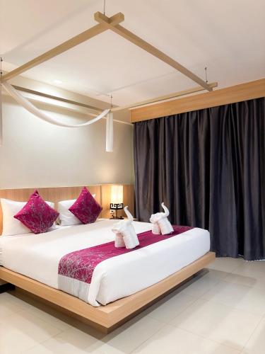 a bedroom with a large bed with purple pillows at Apasari Krabi - SHA Extra Plus in Ao Nang Beach