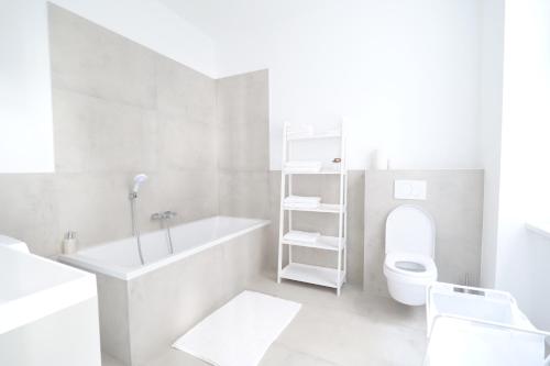 a white bathroom with a tub and a toilet at Apartment Grace Family in Vienna