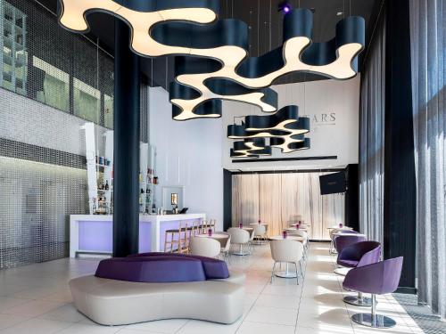 a lobby with purple and white chairs and a bar at Eurostars Book Hotel in Munich