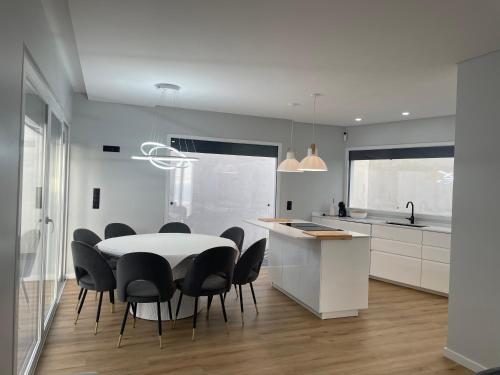 una cucina bianca con tavolo bianco e sedie nere di Sun Temple by Madeira Holiday Rentals a Ribeira Brava