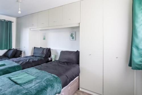 two beds in a room with white walls at NEW Large Contractors House in Hyde 5Guests Long Term WiFi in Hyde