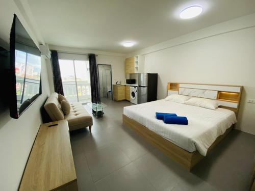 a bedroom with a bed and a couch and a kitchen at 9 Karat Condo by PSR in Pattaya Central
