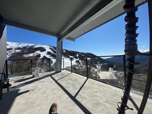 a person standing on a balcony with a view of a mountain at Skyline Penthouse Apartments Falls Creek in Falls Creek