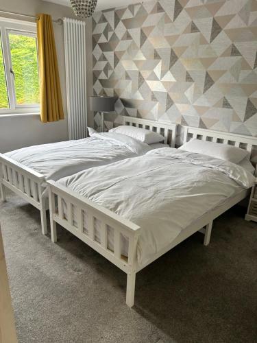 a white bed in a bedroom with a geometric wall at St Johns View in Boston Spa