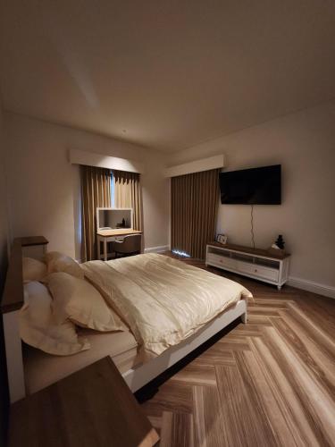 a bedroom with a large bed and a flat screen tv at White Swan Mansion in Ketewel