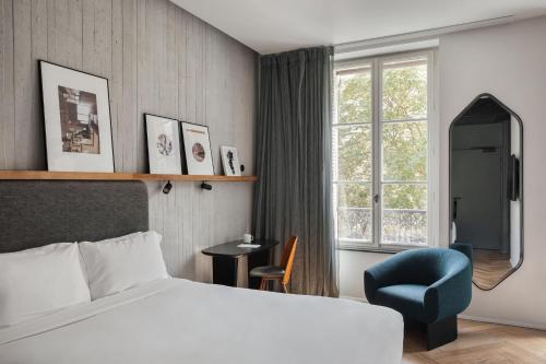 a hotel room with a bed and a chair and a window at Hôtel National Des Arts et Métiers in Paris