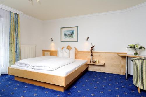 een slaapkamer met een bed en een blauw tapijt bij Hotel Garni Valülla in Ischgl