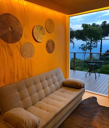 a living room with a couch and a large window at Chalé com banheira e lareira - 20 min de Gramado in Igrejinha