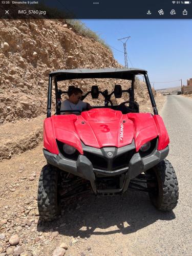 a man driving a red four wheeler on a dirt road at Dar NFis Suites et chambres de luxe dans un havre de paix vue paradisiaque au bord du lac in Lalla Takerkoust