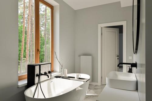 een witte badkamer met een bad en een wastafel bij Villa VILAVI Jurmala in Jūrmala