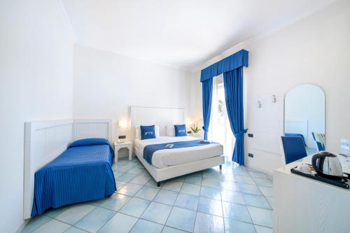 a white bedroom with two beds and a bathroom at Hotel Villa Durrueli Resort & Spa in Ischia