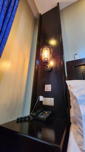a room with a desk with a phone and a lamp at Golden Castle Hotel Hoima in Hoima