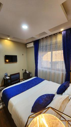 a bedroom with a large bed with blue pillows on it at Golden Castle Hotel Hoima in Hoima