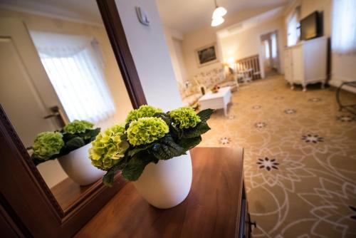 two white vases with flowers on a table in a room at Golden Royal Boutique Hotel & Spa in Košice