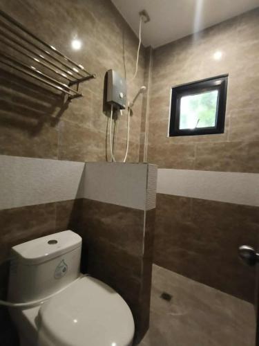 a bathroom with a white toilet and a window at Wilson Hills Travelers Suites in San Juan