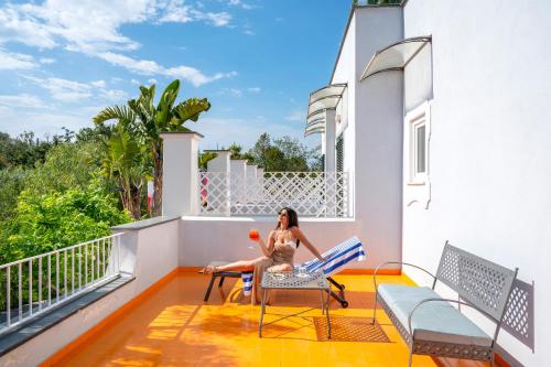 a woman sitting on the balcony of a house at Hotel Villa Durrueli Resort & Spa in Ischia