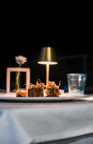 a plate of food on a table with a lamp at Santa Boka in Perast
