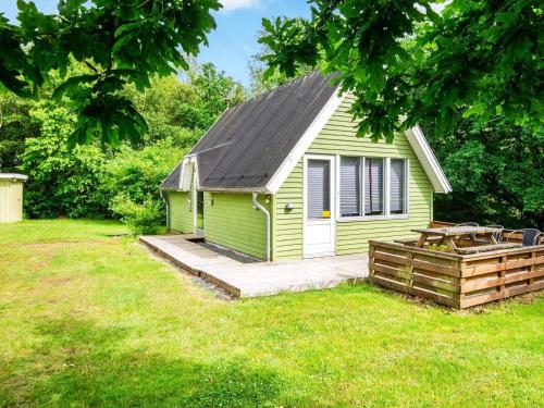 a small green house with a porch in a yard at 5 person holiday home in Grindsted in Tofterup