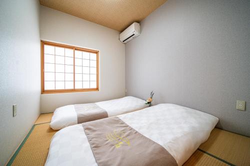 two beds in a room with a window at 夏様小倉町 Convenient house, private house, 5-minute walk from Nijo station in Kyoto