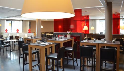 a restaurant with wooden tables and black chairs at ibis Europe Chalon Sur Saone in Chalon-sur-Saône