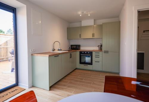 a kitchen with green cabinets and a large window at Loxodonta Lodge - Gîte 4 pers proche de Pairi Daiza in Cambron-Casteau