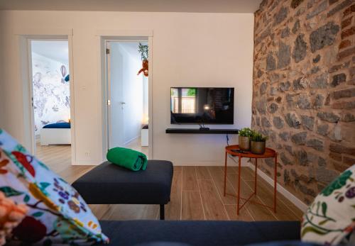 a living room with a couch and a stone wall at Loxodonta Lodge - Gîte 4 pers proche de Pairi Daiza in Cambron-Casteau