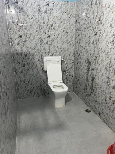 a bathroom with a white toilet in a stall at Hotel Infinity in Rājgīr