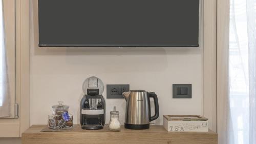 a shelf with a coffee maker and a tv on a wall at Caty's Home in Temù
