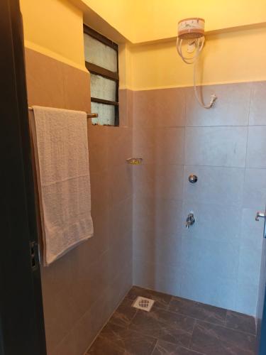 a bathroom with a shower with a white towel at Okoko Enterprises BnB in Kisumu