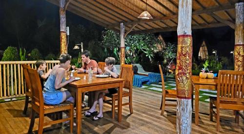 a group of people sitting at a wooden table at Umma Bali Menjangan Retreat in Banyuwedang