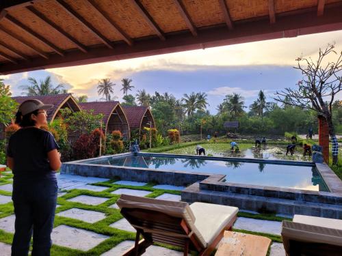 a woman standing in front of a swimming pool at Umma Bali Menjangan Retreat in Banyuwedang