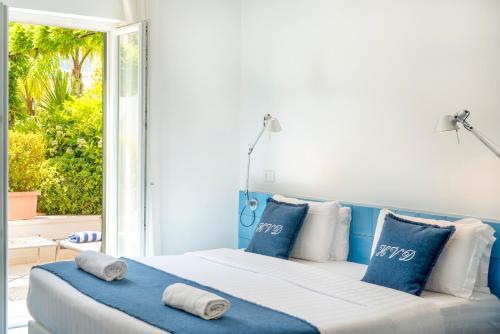 a bedroom with a large bed with blue and white pillows at Hotel Villa Durrueli Resort & Spa in Ischia