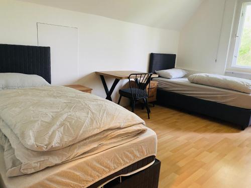 a bedroom with two beds and a table with a chair at 2 Bett Zimmer in Villa im Grunewald in Berlin
