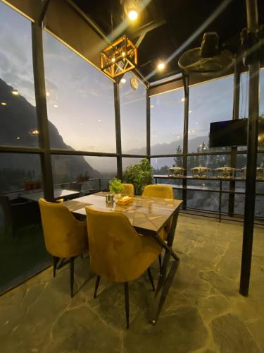 a dining room with a table and yellow chairs at Gumaan Resort in Skardu