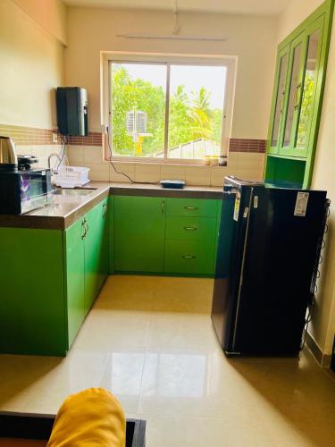 a kitchen with green cabinets and a black refrigerator at Namaste at Beachside 2BHK, with Free Breakfast in Varca