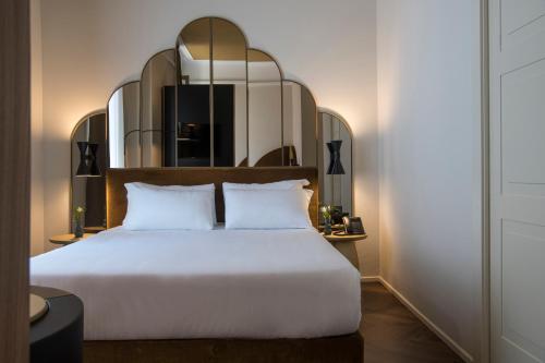 a bedroom with a white bed and a mirror at Palazzo Buenos Aires in Milan
