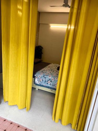 a room with yellow curtains and a small bed at Namaste at Beachside 2BHK, with Free Breakfast in Varca
