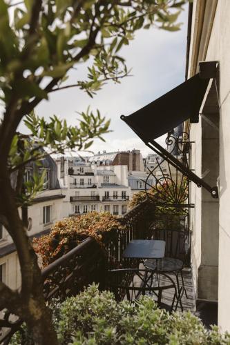 a table and chairs on a balcony with a building at Hotel Bachaumont in Paris