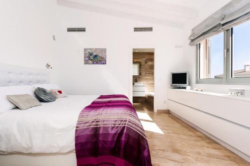 a white bedroom with a large bed with a purple blanket at Bouganvilla House in Ariany