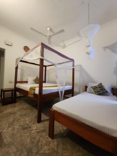 a bedroom with two beds and a ceiling at Karibu House Paje in Paje