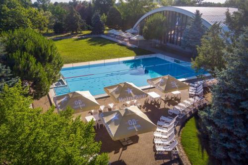 an overhead view of a swimming pool with umbrellas and chairs at Hunguest Hotel Béke in Hajdúszoboszló
