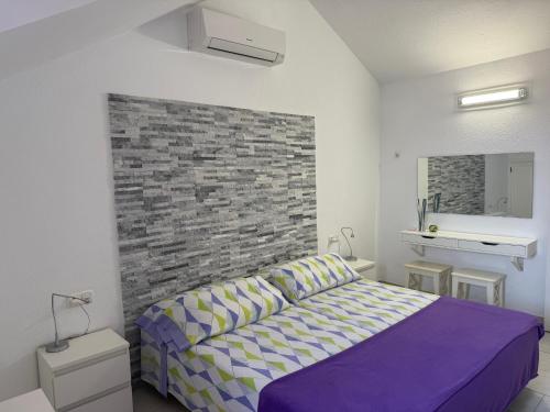 a bedroom with a purple bed and a brick wall at Stunning sea view Tenerife Royal Gardens Resort! in Playa de las Americas