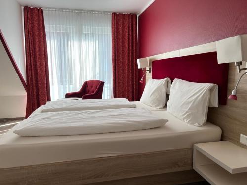 a bedroom with two beds and a red wall at Hotel Sonne am Meer in Norddeich
