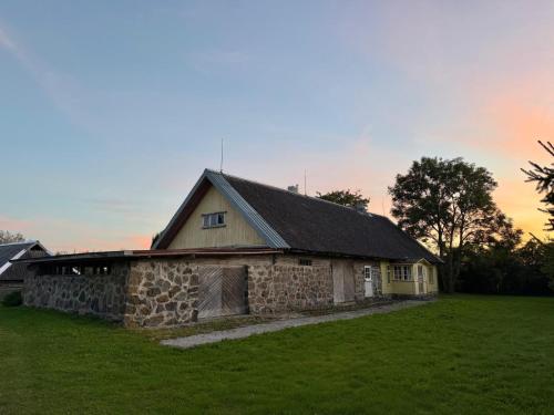 eine alte Scheune aus Stein mit einem Grasfeld davor in der Unterkunft Pärtli-Jaani Elukoda 