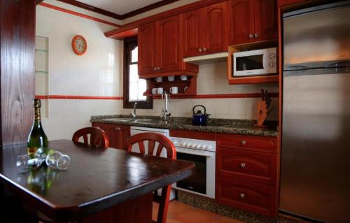 a kitchen with wooden cabinets and a table and a refrigerator at Caleta Dorada in Caleta De Fuste