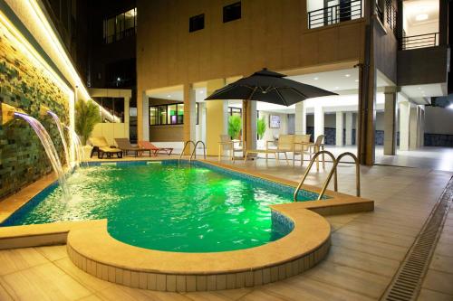 a swimming pool with an umbrella in a building at Ethan Palace in Kofa