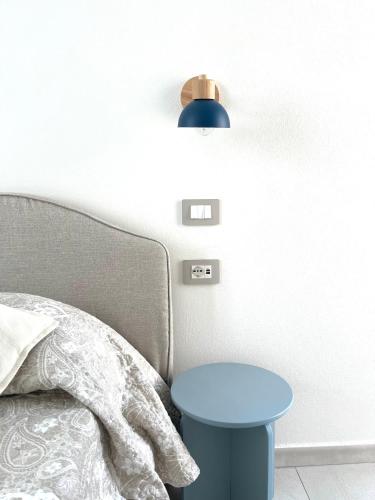 a bed with a blue stool next to a blue lamp at Domus Apartments in Teulada