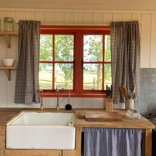 a kitchen with a large white sink and a window at Secluded off grid Shepherd's Hut in Minchinhampton